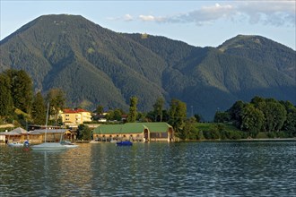 Tegernsee with sailing boats and boat huts, warm evening light, town Tegernsee, mountain Wallberg,