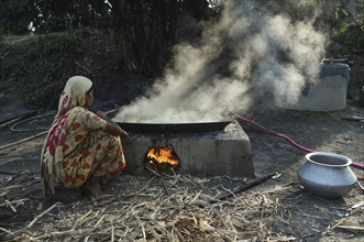 Workers boiling sugarcane juice as they are making Gur (jaggery) in a village on December 10, 2021