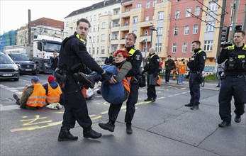 Police officers carry a Last Generation activist away from a road blockade, Berlin, 24 04 2023