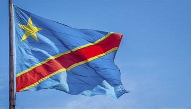 The flag of the Democratic Republic of the Congo flutters in the wind, isolated against a blue sky