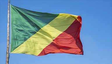 The flag of Congo flutters in the wind, isolated against a blue sky