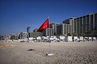 Red flag, swimming prohibited, on the beach in front of Hotel Marriot Resort Palm Jumeirah, behind