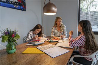 Homeschooling, during the lockdown in January 2021, mother helps her two daughters, at home,