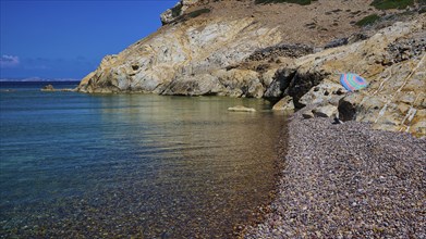 Coastal landscape with blue sea, rocky beach, imposing rock formations under a clear sky, Lambi