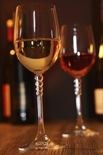 Close-up of two glasses of wine with wine bottles in the background