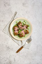 Top view of plate with meatballs with fresh green peas and cranberry sauce on grey stone background