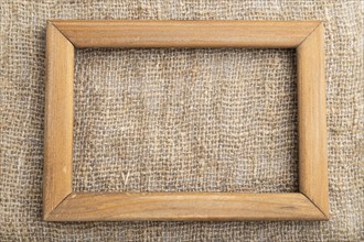 Wooden frame on smooth brown linen tissue. Top view, flat lay, natural textile background and