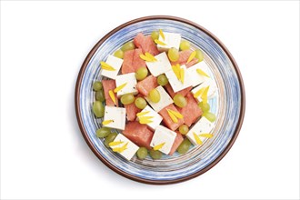 Vegetarian salad with watermelon, feta cheese, and grapes on blue ceramic plate isolated on white