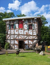 Traditional half-timbered house with bright red windows and red door, green windows and cradle,