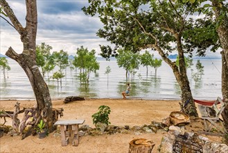 Woman on a swing on a flooded stretch of beach on the island of Koh Yao Noi, water level, climate