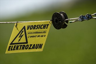 Electric fence on a pasture, warning sign, electric shock