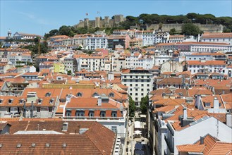 View over a city with many houses and red roofs, in the background a castle on a hill, viewpoint,