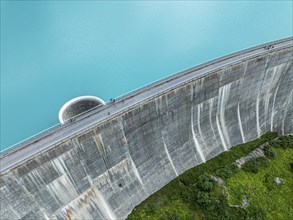 Dam of the Moiry lake, Lac de Moiry, turquoise glacial water, water overflow, tourists, aerial