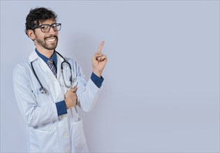 Happy bearded doctor pointing at advertising space isolated. Beard doctor pointing a promotion with