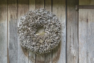 Door wreath made of natural materials in front of a house wall, North Rhine-Westphalia, Germany,