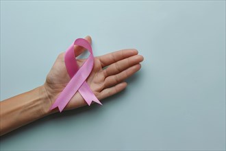 Woman's hand holding pink breast cancer awareness ribbon. KI generiert, generiert, AI generated