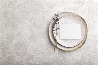 White paper invitation card, mockup with lavender on ceramic plate and gray concrete background.