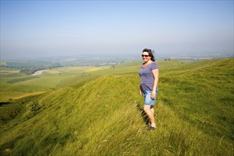 Woman standing on steep chalk scarp slope on downland at Cherhill Down, Wiltshire, England, United