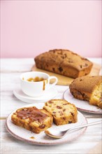 Homemade cake with raisins, almonds, soft caramel on a white and pink background. Side view, close