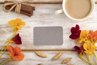 Gray paper business card mockup with orange nasturtium flower and cup of coffee on white wooden