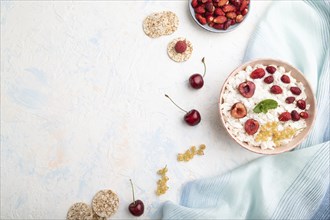 Rice flakes porridge with milk and strawberry in ceramic bowl on white concrete background and blue