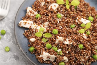 Quinoa porridge with green pea and chicken on ceramic plate on a gray concrete background and