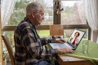 Symbolic image of telemedicine, elderly patient speaking to a doctor in a video conference from