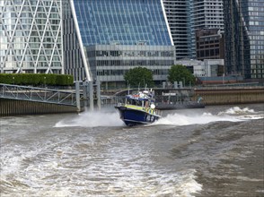 Metropolitan police speedboat motor launch travelling at high speed, Canary Wharf, River Thames,