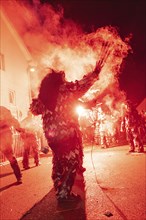 Person in costume creates a cloud of smoke at a night event, carnival, Schellbronn night