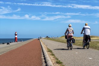 North Sea dyke near Westkapelle, Westkapelle Laag lighthouse, cyclists on the Zeeuwse Wind Route