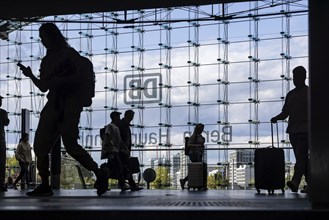 Central station, travellers in front of the glass facade with the logo of Deutsche Bahn AG. Berlin,