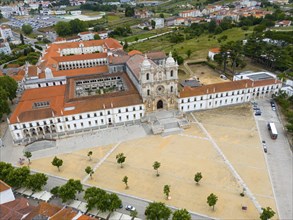 An aerial view of a historic monastery with red roofs in a town with surrounding landscape, Aerial