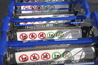 Close up of line of stacked luggage trolleys with rules about use, Malaga airport, Spain, Europe