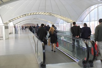 Passengers pulling luggage bags along a bright corridor, Atocha railway station, Madrid, Spain,