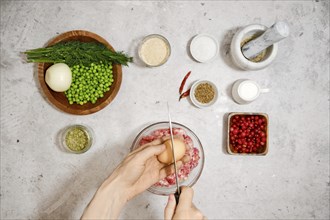 Top view of breaking an egg into a bowl with minced meat. Process of making scandinavian meatballs