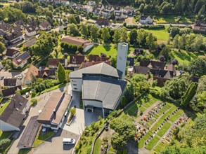 Church with adjoining cemetery in a picturesque village surrounded by green hills and nature,