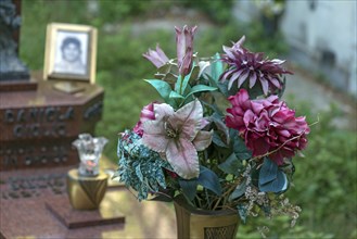 Faded plastic flowers on a grave in the Staglieno Monumental Cemetery, Cimitero Monumentale di