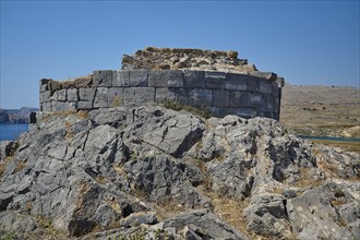 Crumbling ancient ruins in a rocky landscape under a blue sky, tomb of Cleovoulos the Lindian,