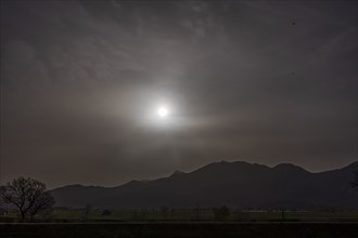 Sahara dust covers the sun in front of a mountain landscape, spring, Loisach-Lake Kochel-Moore,