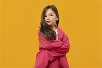 Studio portrait of playful young girl wrapped in jacket of her mother