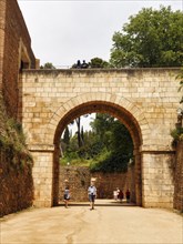 Tourists, walkers go through large gate, old town of Granada, Andalusia, Spain, Europe