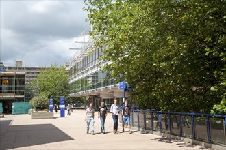 Male students walking on campus near the library building at the University of Bath, England,