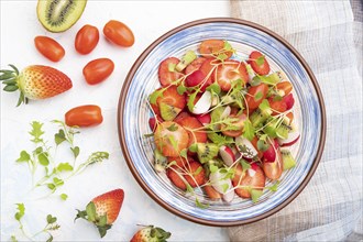 Vegetarian fruits and vegetables salad of strawberry, kiwi, tomatoes, microgreen sprouts on white