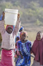 Girl carrying a heavy bucket of water on her head, Maraban Dare, 07/02/2024