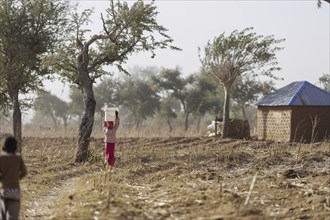 Girl carrying a heavy bucket of water on her head, Maraban Dare, 07/02/2024