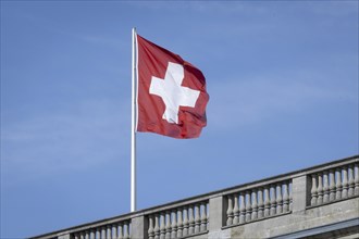 The Swiss flag flies against a blue sky on the roof of the Swiss Embassy in Berlin, 28 March 2024