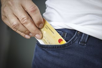 A person pulls a credit card out of his trouser pocket in Berlin, 09/08/2024