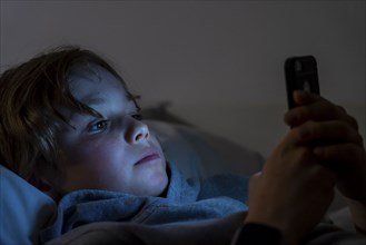 A boy plays computer games on a mobile phone, smartphone