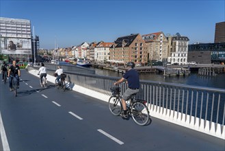 Cyclists on the Inderhavnsbroen cycle and footpath bridge, over the harbour, at Nyhavn, Copenhagen