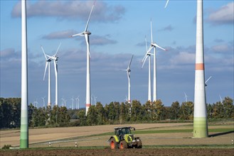 Farmer working in the fields, with a tractor, wind farm above the village of Lichtenau,